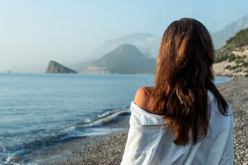 Obraz premium beautiful young woman on vacation, a woman stands with her back to the sea