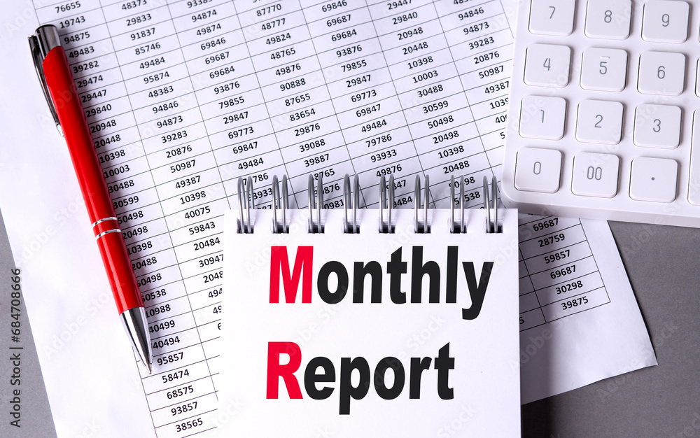 Poster monthly report text on notebook with pen, calculator and chart on grey background