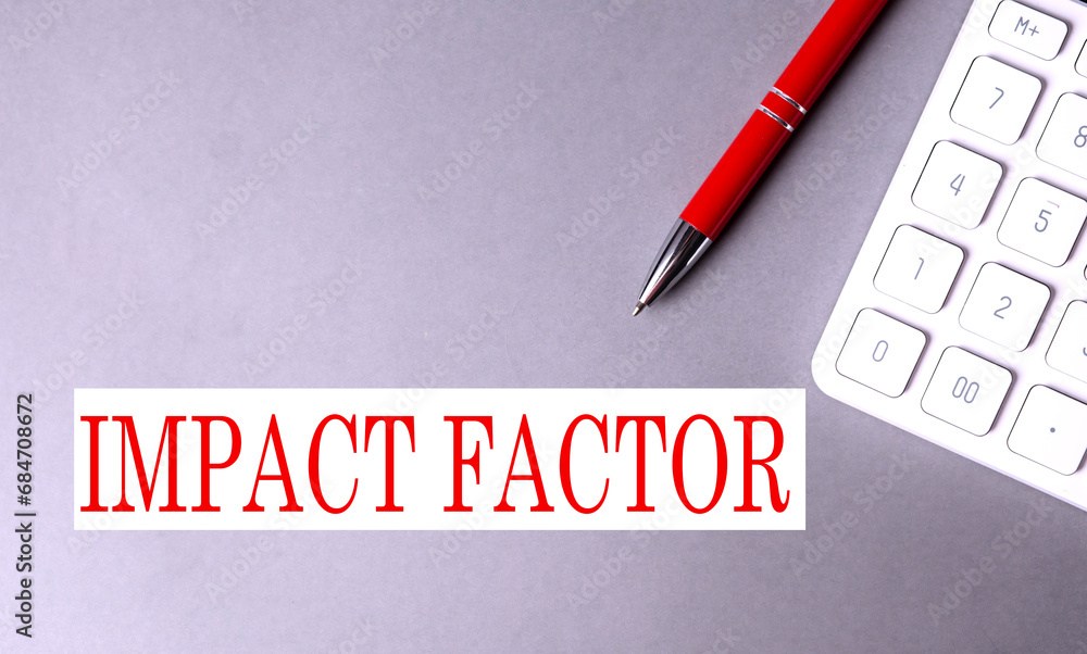 Aufkleber impact factor text written on a gray background with pen and calculator