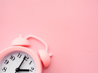 Pink background with alarm clock at 2am 2pm and copy space to add text 