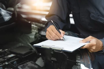 Foto op Plexiglas Auto check up and car service shop concept. Mechanic writing job checklist to clipboard to estimate repair quotation to client at workshop garage. © Pormezz