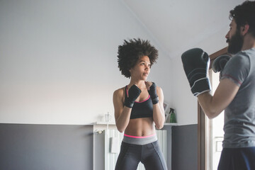 Young multiethnic woman at home training with coach doing boxe exercise - Powered by Adobe
