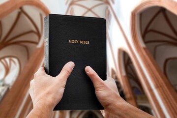 Christian person reading bible book in Catholic temple.