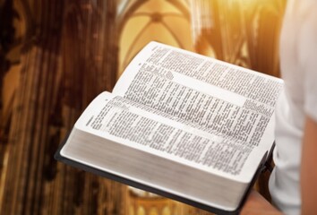 Christian person reading bible book in Catholic temple.