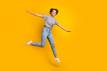 Full length portrait of cheerful pretty person jump arms wings flying empty space isolated on yellow color background