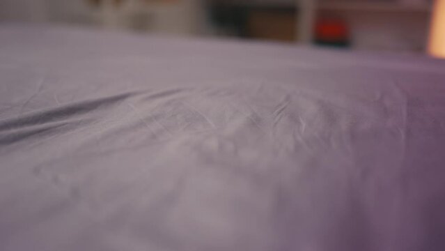 Female hand touching smooth cotton bedsheet after laundry, soft clean fabric