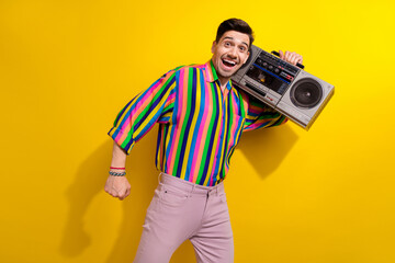 Photo of crazy man in vintage clothing enjoy hear favorite soundtracks from his childhood using boombox isolated on yellow color background