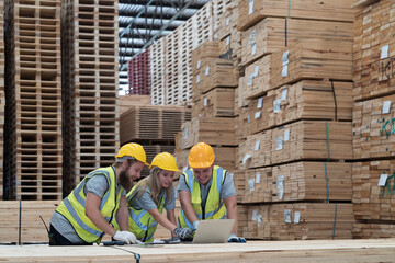 Group of male and female warehouse workers working laptop computer at wooden warehouse storage....