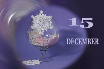 Calendar for December 15: numbers 15, the word December, glass with decorative snowflakes on a...