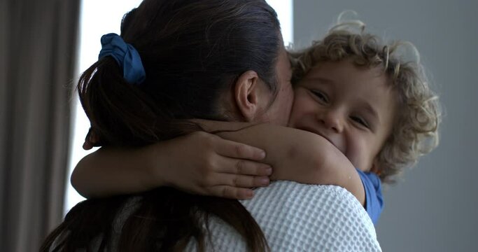 Super slow motion of carefree happy smiling mother and little son kid are having fun to play together just woken up in hotel room during holidays family travel vacation trip.