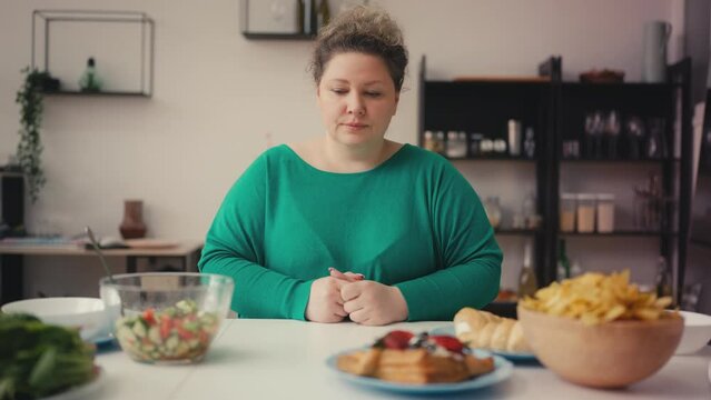 Overweight woman choosing between healthy food and unhealthy snacks, dieting