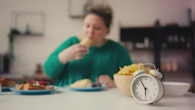 Plus size woman overeating sweets and junk food before 6pm, intermittent fasting