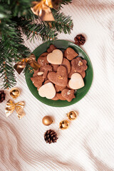 Gingerbreads, line cakes arranged on a green plate beneath the Christmas tree capturing a bird's-eye view of festive sweetness. The warm, spicy aroma of gingerbread mingles with the evergreen scent.