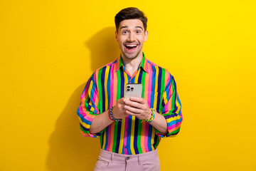 Photo of amazed funny guy in striped shirt use smartphone enjoy sms he received grocery store...