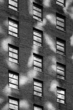Monochrome black and white brick city apartment building with windows and reflected sunlight patterns in vertical orientation