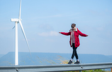 On the background of windmills, A young woman in a red jacket is enjoying her winter vacation.