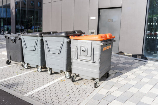 Row of worn out recycing and waste bins in a car park at the back of a modern office building