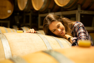 Portrait of a young woman surrounded by wine barrels In her winery