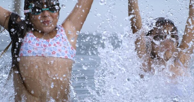 Super slow motion of little girls friends or sisters  in colorful swimsuit and water goggles is having fun to swim underwater and splash water in swimming pool during summer holidays travel vacation.