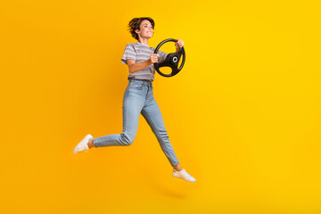 Full length profile portrait of lovely active person jumping hands hold wheel empty space isolated on yellow color background