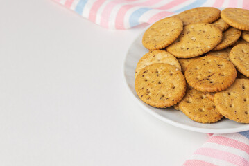 Oval shortbread or herbal crackers in white plate on stripped table napkin with copy space