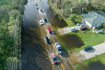 Hurricane flooded street with moving cars and surrounded with water houses in Florida residential...