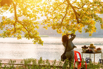 Tourists enjoy and take photos on bank of the Hoan Kiem Lake ( Ho Guom) or Sword lake in the center...