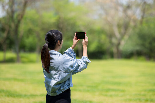 Woman use cellphone to take photo at park