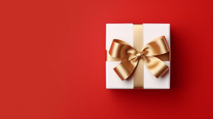 Golden bow and ribbon on white box on red background as Christmas gift concept
