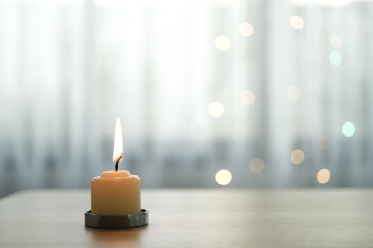 Candle on table with bokeh light and curtain