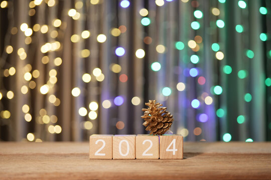 2024 wooden blocks and pine on wooden table with bokeh lighting