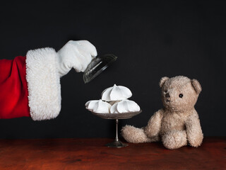Santa Claus treats teddy bear to meringue, a sweet treat. Celebrate Christmas en child care concepts.