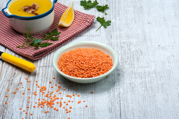 High angle view of red lentils in a bowl on a white vintage wooden table with a bowl of classical Turkish red lentil soup