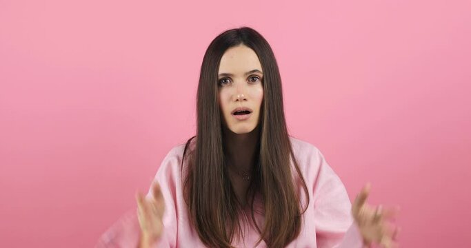 Brunette indignant woman showing blah blah blah gesture with hands isolated on studio pink background. Empty promises, blah concept. Lier, not interested. Annoyed girl making bla bla bla hand gesture