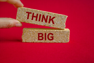 Think big symbol. Brick blocks with red words Think big. Beautiful red background. Businessman...