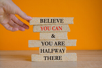 Concept red words Believe you can and you are halfway there on brick blocks on a beautiful wooden...
