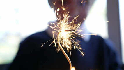 Sparkler burning on birthday cake celebration with child in background celebrating during party day