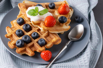 Delicious waffles with whipped cream, strawberries and blueberries
