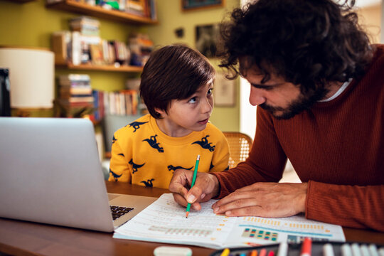 Dad helping son with homework at home. Little boy studying homeschooling with father