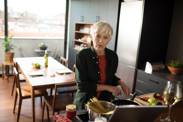 Elegant Senior Woman Preparing Pasta in a Modern Kitchen