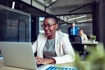 Smiling businesswoman working on laptop in office