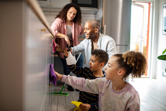 Young mixed family cleaning the kitchen together at their home
