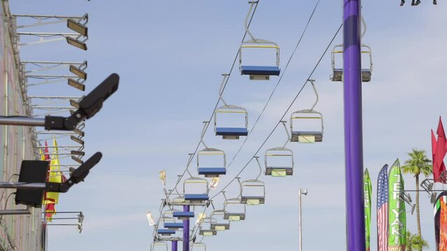 This video shows empty chairlifts going back and forth with a blue sky in the background. 