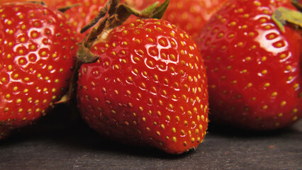 Close up of ripe red strawberries on a black background. Fresh organic strawberries. Raw vegan summer snack. Healthy, wholesome and natural food concept.