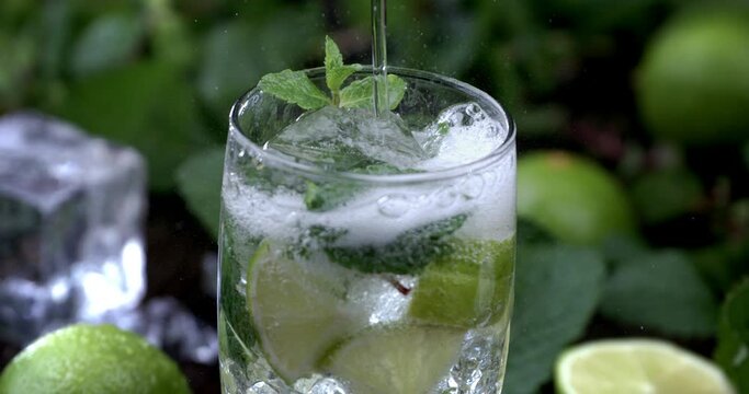 Soda Falling into ice cube on Glass of Fresh Mojito Cocktail. Super Slow Motion filmed on High Speed Cinema Camera at 1000fps.