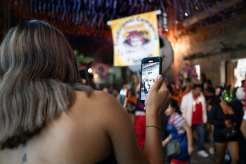 blond young girl filming with smartphone party on the street for social media posting 