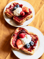 Detail of two toasts of brioche bread with jams and red fruits and blueberries