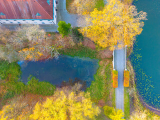 Beautiful travel or tourism style look down aerial of pedestrian foot bridge across River at park with colorful fall foliage lining the river banks in autum