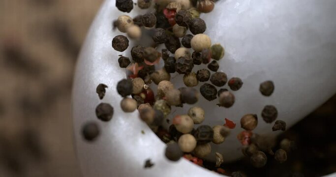 Super slow motion macro of dry mixed flavorful and aromatic peppercorn are being grinded in mortar on rustic wooden table in restaurant kitchen Filmed on High Speed Cinema Camera, 1000 fps.