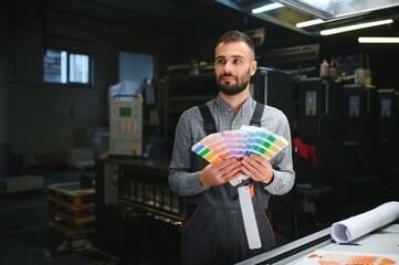 Typographer standing with color swatches at the printing manufacturing